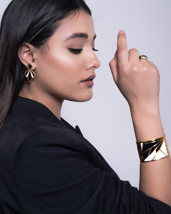Elevate your ensemble with these striking Art Deco-inspired earrings, a bold fusion of vintage glamour and modern edge. Crafted in copper with a rich gold plating, the geometric silhouette channels the elegance of the 1920s with a contemporary twist. - Design: Angular and symmetrical, the earrings feature clean lines and architectural shapes reminiscent of classic Art Deco motifs. - Finish: Polished gold plating adds warmth and sophistication, while the black enamel accents provide dramatic contrast and depth. - Style: Perfect for evening wear or statement styling, these earrings pair effortlessly with minimalist or monochrome outfits, adding a touch of opulence and intrigue.